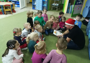 Dzieci uważnie słuchają książki czytanej przez tatę Gabrysi