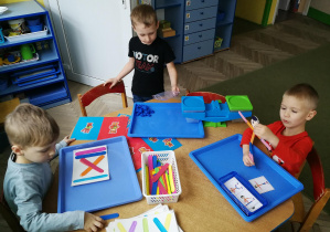Chłopcy pracują z materiałem rozwojowym M. Montessori: "Ćwiczący chłopiec", "Waga i misie", "Kolorowe patyczki i wzory"