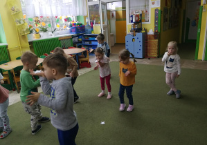 Przedszkolaki zdmuchują papierowe gwiazdki z dłoni