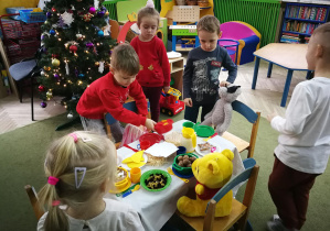 Dzieci zapraszają misie i lale na wigilijną wieczerzę