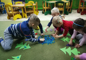 Dzieci układają diamenciki na choinkach w liczbie zgodnej z ilością dziurek w kształtach