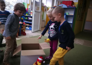 Dzieci wkładają do pudełka zabawki w liczbie zgodnej z ilością otworów w wylosowanym kształcie