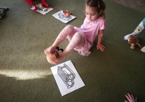 Marysia przenosi maskotkę za pomocą stóp na ilustrację sanek