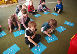 Dzieci przeliczają kropki na kartach ze wzorami