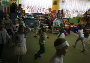 Dzieci poruszają się po sali z pietruszkami w rytmie dzwięków tamburyna