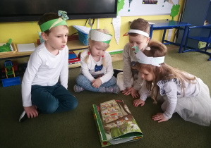 Janek, Hania, Antoś i Marysia oglądają pietruszkę z książki "Przekroje warzyw i owoców"