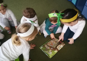 Oliwka, Gabryś, Lenka, Hania oglądają pietruszkę z książki "Przekroje warzyw i owoców"