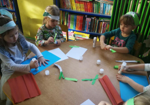 Dzieci przy żółtym stoliku tworzą prace plastyczne "Pietruszki na grządce"