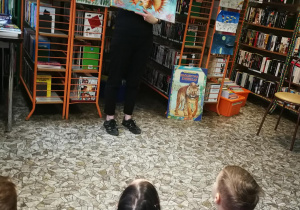Pani bibliotekarka pokazuje dzieciom jedną z książek przestrzennych