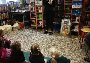 Pani bibliotekarka prezentuje dzieciom zasoby książek o misiu Puchatku i jego przyjaciołach