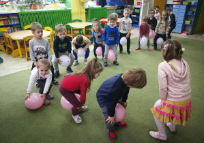 Dzieci trzymają balony kolanami