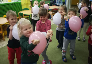 Dzieci trzymają balony łokciami