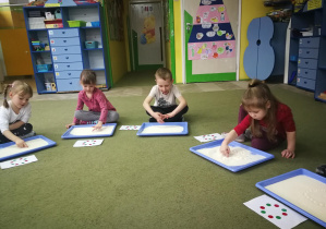Dzieci rysują wzór na tackach z manną w rytmie piosenki "Nasze przedszkole"