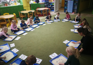 Dzieci "wygrywają" piosenkę "Nasze przedszkole" na kaszy mannie, tworząc wzór kropek ułożonych w koło