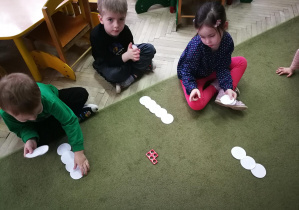 Mateusz, Tymon i Hania układają bałwanki z 5 kół origami zgodnie z liczbą otworów w wylosowanym kształcie Numicon