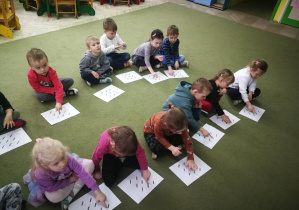Dzieci "rysują" palcami ukośne kreski na wzorze w rytmie piosenki "Jeż"