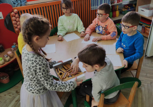 Dzieci przy stolikach częstują się słodkościami od Julki