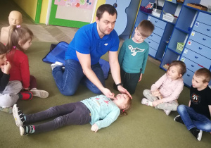 Ratownik medyczny pokazuje dzieciom jak udzielić pierwszej pomocy