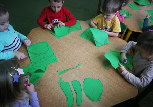 Dzieci przy zielonym stoliku wycinają kapusty