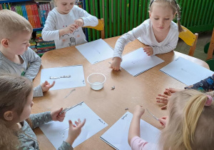 Dzieci przy żółtym stoliku wyklejają wzór - kreska/linia pionowa