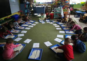 Przedszkolaki rysują palcami na kaszy mannie linie pionowe w rytmie piosenki "Termometr"