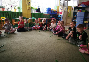 Dzieci wygrywają rytm piosenki "Pajacyk" za pomocą plastikowych patyczków/pałeczek