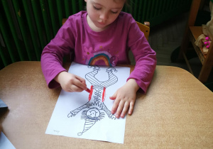 Lena rysuje kredką pastelową dwie pionowe linie do piosenki "Pajacyk"
