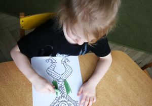Gabrysia rysuje kredką pastelową dwie pionowe linie do piosenki "Pajacyk"