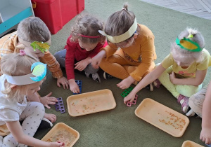 Dzieci układają ziarna kukurydzy w otworach klocków Numicon
