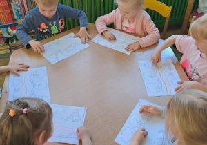 Dzieci przy żółtym stoliku odtwarzają graficznie wzór dwóch poziomych linii