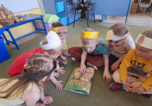 Dzieci oglądają przekrój ziemniaka w książce "Przekroje warzyw i owoców"