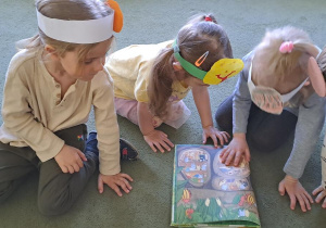 Remik, Marysia, Gabrysia i Antoś oglądają przekrój ziemniaka w książce "Przekroje warzyw i owoców"