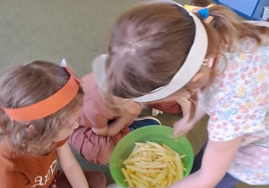 Michasia pokazuje dzieciom pokrojone na frytki ziemniaki