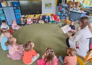 Dzieci uważnie słuchają czytanej przez mamę Oliwki książki o przygodach Zuzi