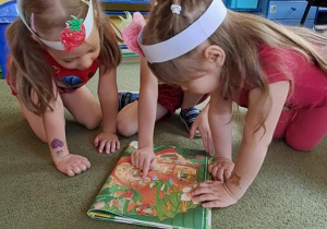Dzieci oglądają przekrój truskawki w książce