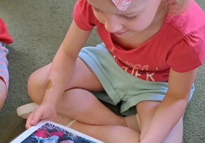 Gabrysia ogląda ilustrację truskawek