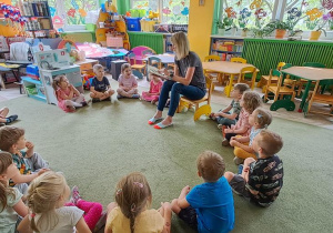 Dzieci słuchają czytanej przez mamę Jasia książki o przygodach Wilka