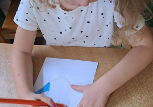 Laura koloruje odrysowaną na kartonie dłoń
