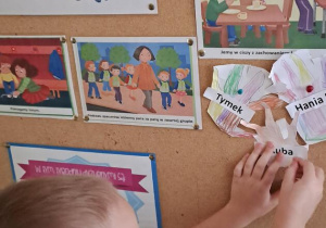 Kuba przyczepia papierową dłoń na tablicy z zasadami przedszkolnymi Puchatków