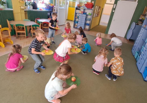 Dzieci starają się zrobić przysiad z jabłkiem na podstawce