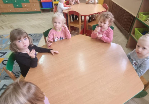 Dzieci jedzą przy stolikach owoce