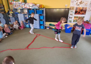 Tymek, Marysia i Leon spacerują po literce "A" ułożonej z liny