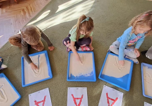 Laura, Marysia, Olaf i Gabrysia rysują litery "A" na kaszy mannie