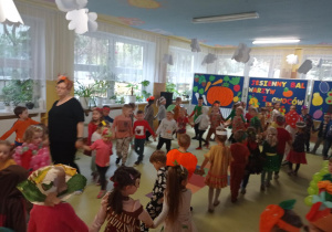 Dzieci przebrane w jesienne stroje tańczą w kołach do piosenki