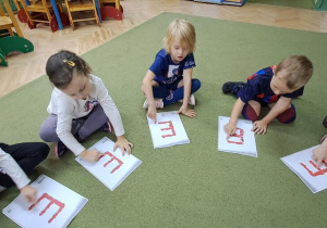 Misia, Hania, Gabrysia, Jaś i Marysia paluszkami "rysują" literę "E" na wzorach, śpiewając piosenkę "Ewelina"