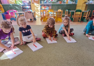 Dzieci rytmicznie do piosenki przesuwają palce po wyklejonych wzorach litery "I"