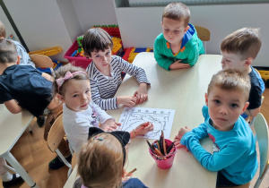 Dzieci przy stoliku tworzą wspólną pracę