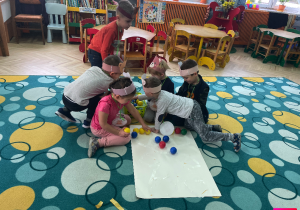 Dzieci tworzą misia z piłeczek.
