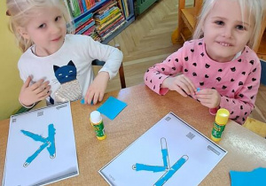 Hania i Nadia wyklejają litery "K" niebieską wydzieranką