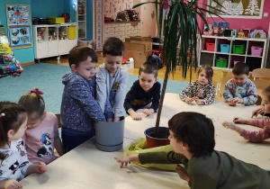 Dzieci przy stolikach, szykują roślinie odpowiednie warunki do życia
